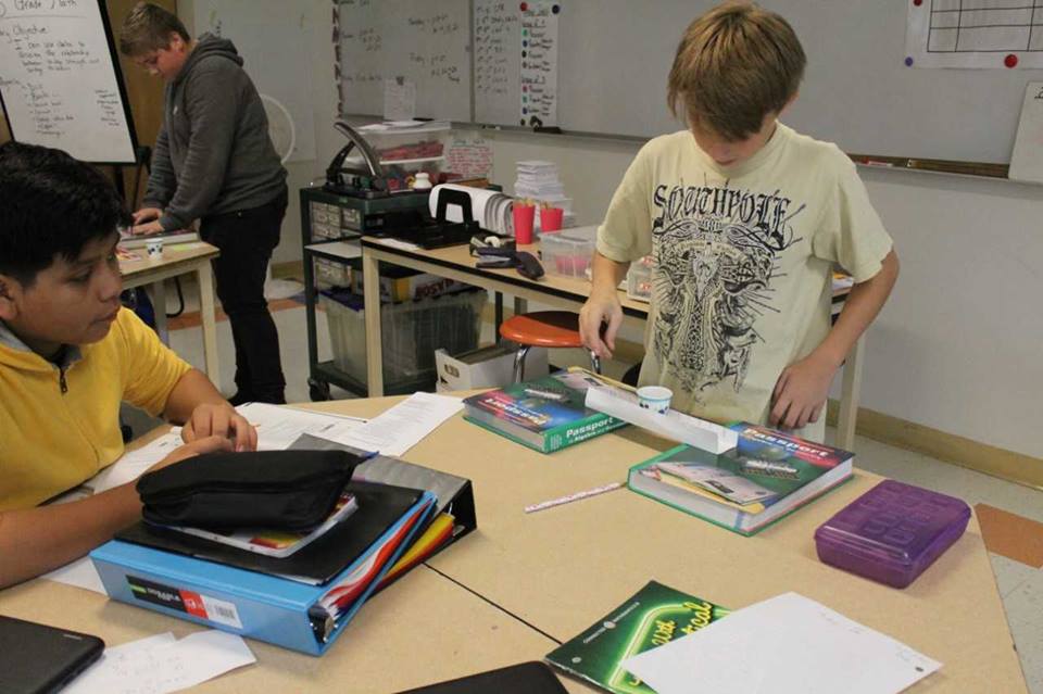 3 middle school students in a math classroom building models of bridges